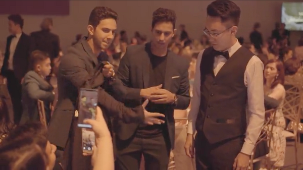 The French Twins performing at a luxury private gala with guests around a table.