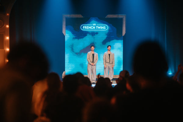 The French Twins on stage in front of a Merci finale LED with fireworks.