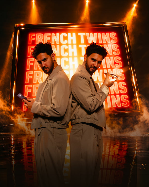 The French Twins official show poster with neon signage and stage smoke.