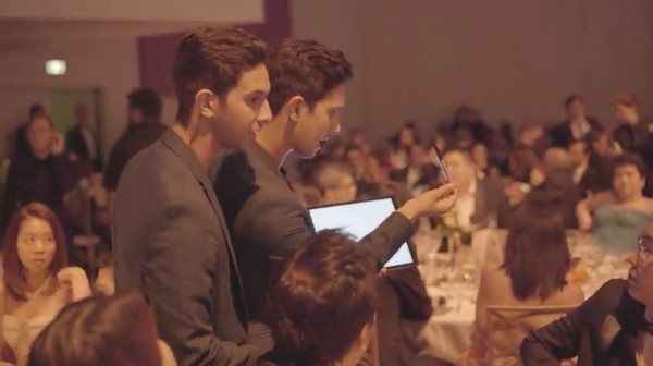 The French Twins performing at a private corporate dinner with the audience watching closely from their tables.